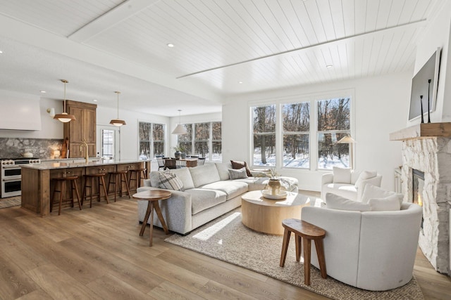 living area with light wood-type flooring, wooden ceiling, recessed lighting, and a glass covered fireplace