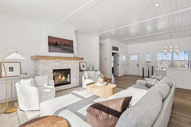 living room with a stone fireplace, wood finished floors, beam ceiling, and a healthy amount of sunlight