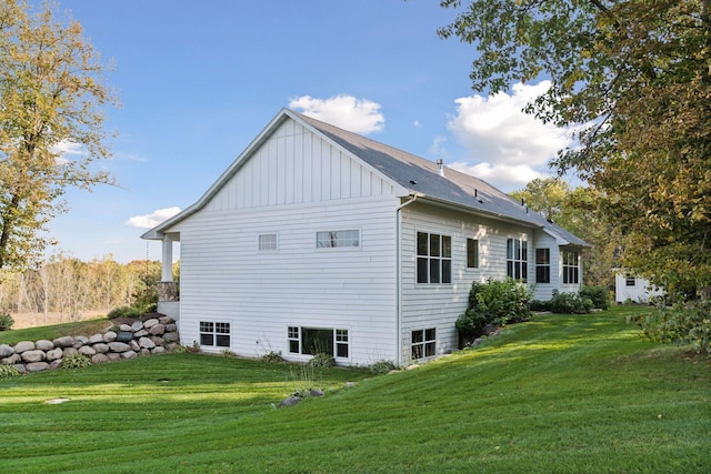 rear view of house with board and batten siding and a lawn