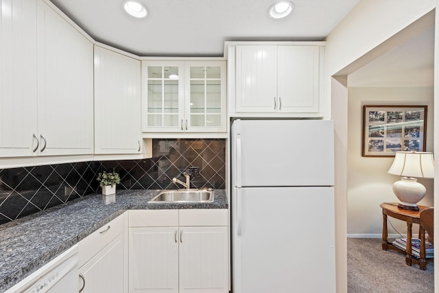 kitchen featuring carpet, white appliances, a sink, decorative backsplash, and dark countertops