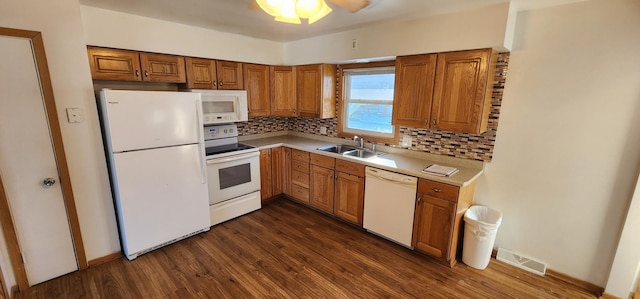 kitchen with white appliances, visible vents, dark wood-type flooring, light countertops, and a sink