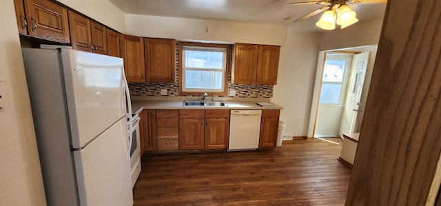 kitchen with tasteful backsplash, light countertops, dark wood-type flooring, a sink, and white appliances