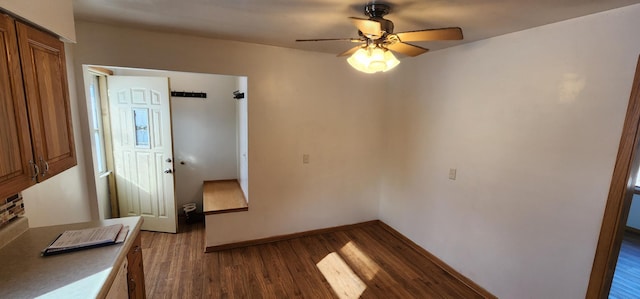 unfurnished dining area with dark wood-style floors, baseboards, and a ceiling fan