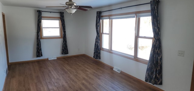 empty room with visible vents, ceiling fan, baseboards, and wood finished floors