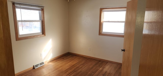 empty room featuring visible vents, baseboards, and wood finished floors