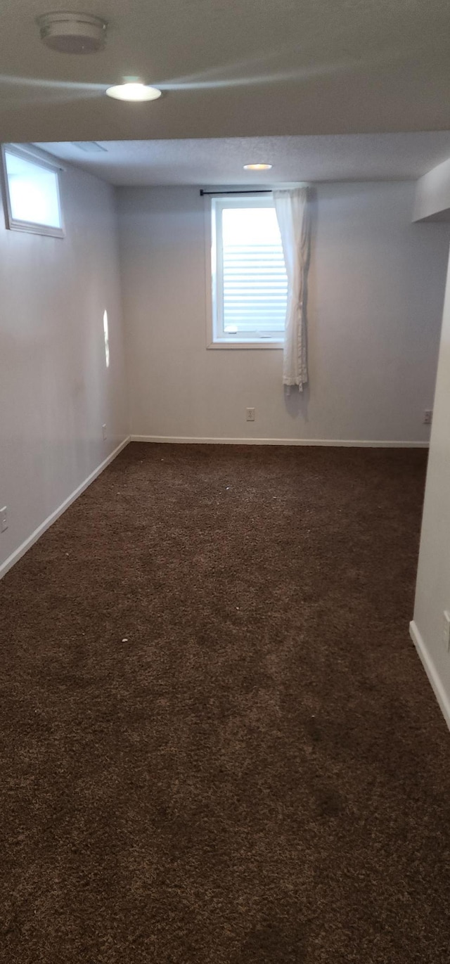 empty room with dark carpet and baseboards