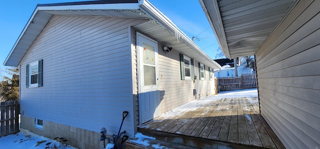 view of snowy exterior with a deck and fence