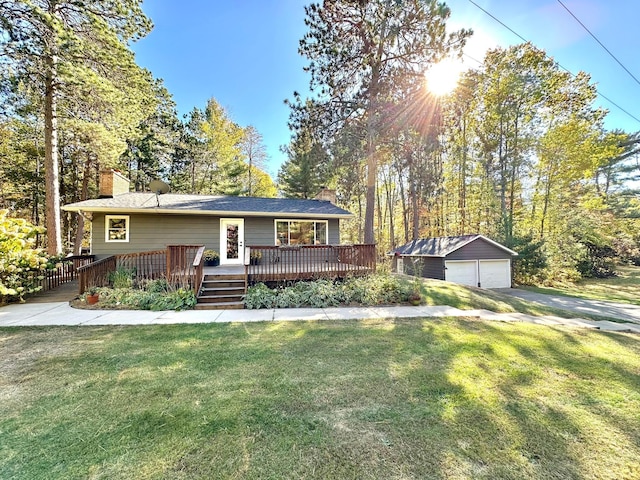 view of front facade with a detached garage, a chimney, a front yard, an outdoor structure, and a wooden deck