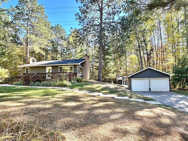 view of front of property featuring a chimney, a detached garage, an outbuilding, a deck, and a front lawn