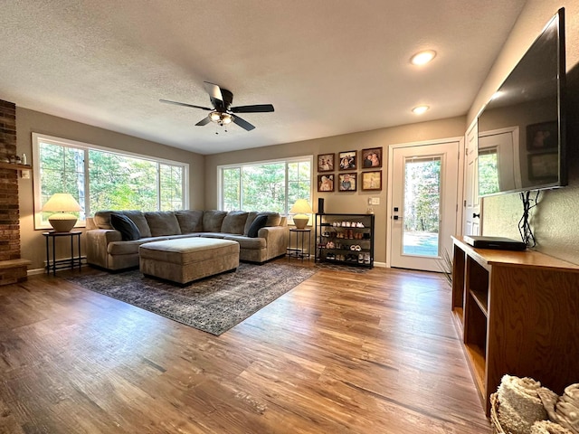 living area with ceiling fan, baseboards, dark wood finished floors, and a textured ceiling