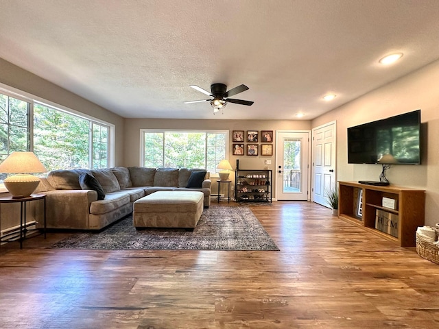 living room featuring a ceiling fan, recessed lighting, dark wood-style flooring, and a textured ceiling