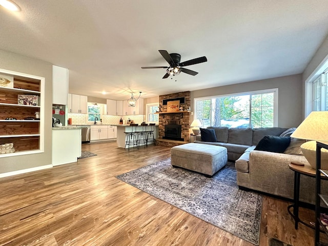 living area with light wood finished floors, ceiling fan, and a fireplace