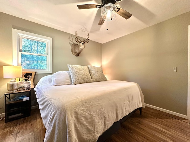 bedroom with dark wood-style flooring, ceiling fan, and baseboards