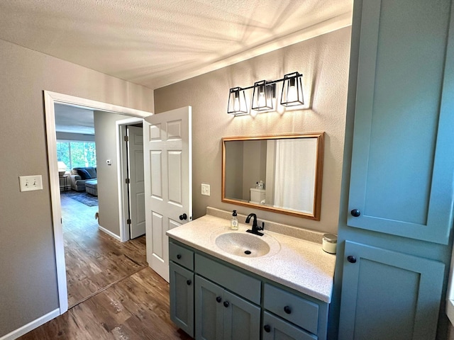 bathroom featuring baseboards, vanity, a textured ceiling, and wood finished floors