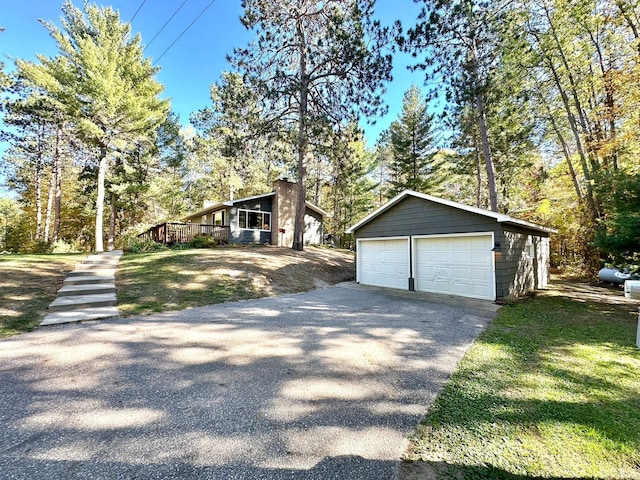 view of side of property with a garage, a deck, and an outbuilding