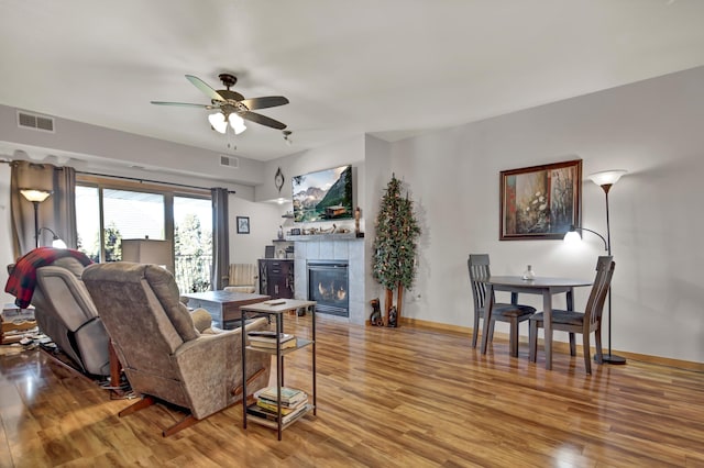 living area featuring visible vents, a fireplace, baseboards, and wood finished floors