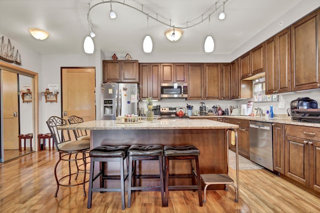 kitchen featuring stainless steel appliances, a center island, pendant lighting, and light wood finished floors