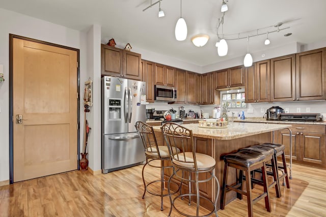 kitchen featuring light wood-type flooring, a kitchen island, appliances with stainless steel finishes, and pendant lighting