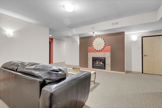 living room with a tiled fireplace, carpet flooring, and visible vents