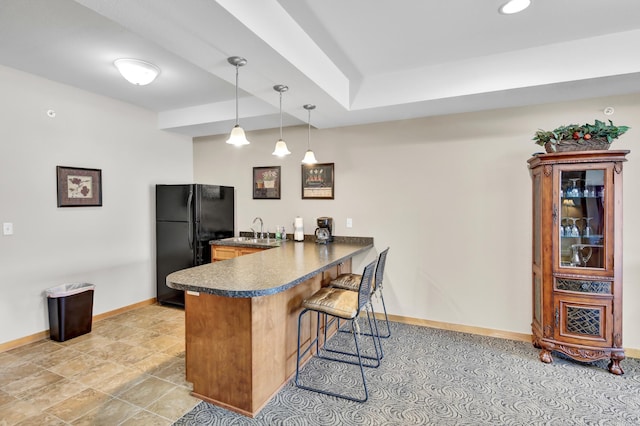 kitchen with dark countertops, a breakfast bar, freestanding refrigerator, a peninsula, and pendant lighting