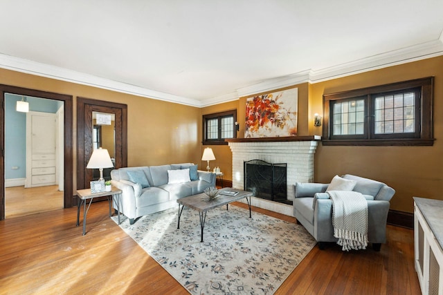 living room featuring baseboards, a fireplace, wood finished floors, and crown molding