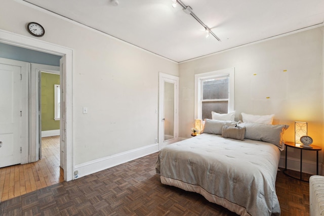 bedroom with baseboards, radiator heating unit, ornamental molding, parquet floors, and track lighting