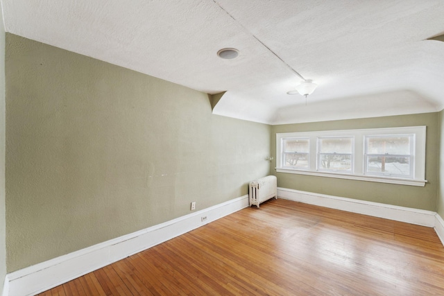 empty room featuring radiator, baseboards, and wood finished floors