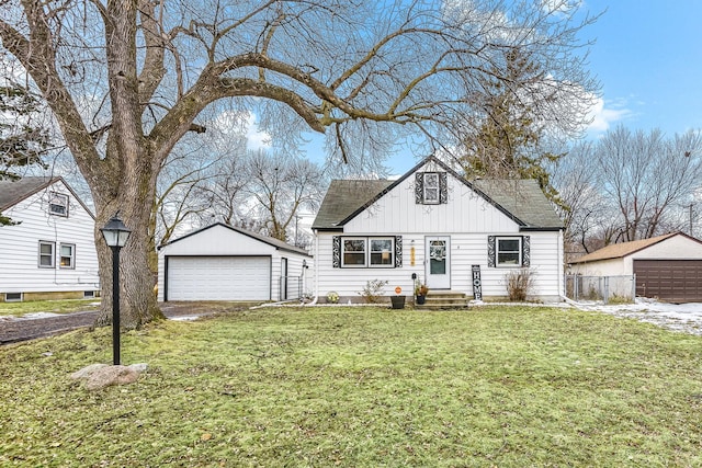 bungalow with an outbuilding, a shingled roof, board and batten siding, a garage, and a front lawn