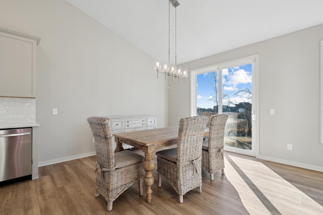 dining area with baseboards, light wood finished floors, vaulted ceiling, and an inviting chandelier