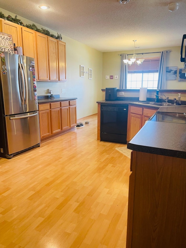 kitchen with light wood finished floors, black dishwasher, dark countertops, freestanding refrigerator, and pendant lighting