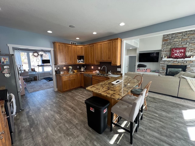 kitchen with light stone counters, a breakfast bar area, a peninsula, a sink, and open floor plan