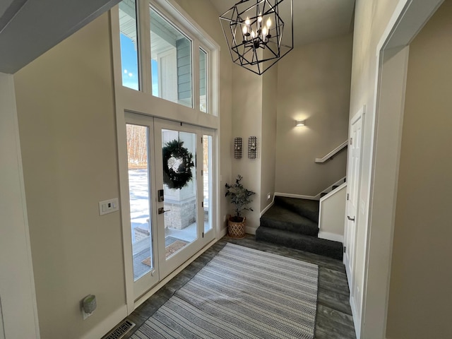 foyer with a high ceiling, visible vents, baseboards, stairs, and dark wood-style floors