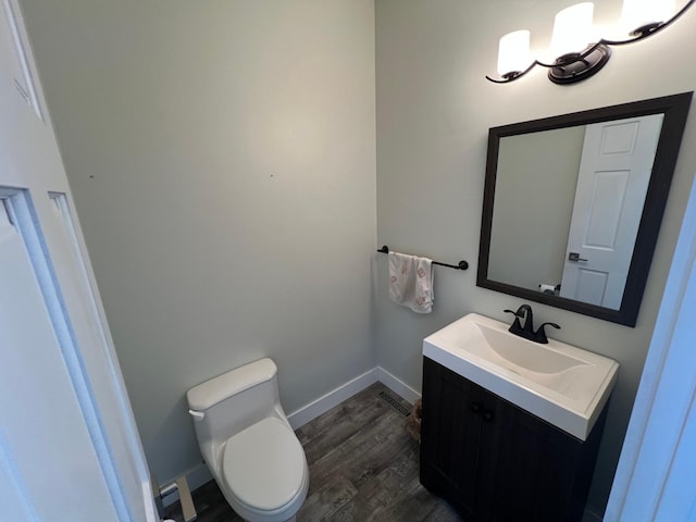 half bathroom featuring toilet, wood finished floors, visible vents, vanity, and baseboards