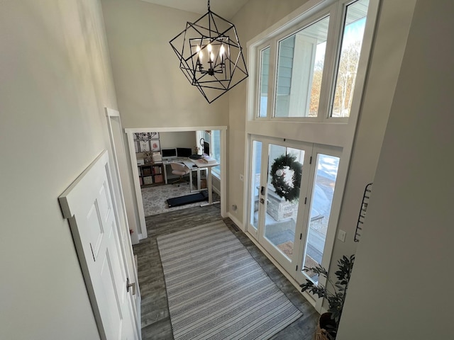 foyer with a towering ceiling, a notable chandelier, and dark wood-style flooring