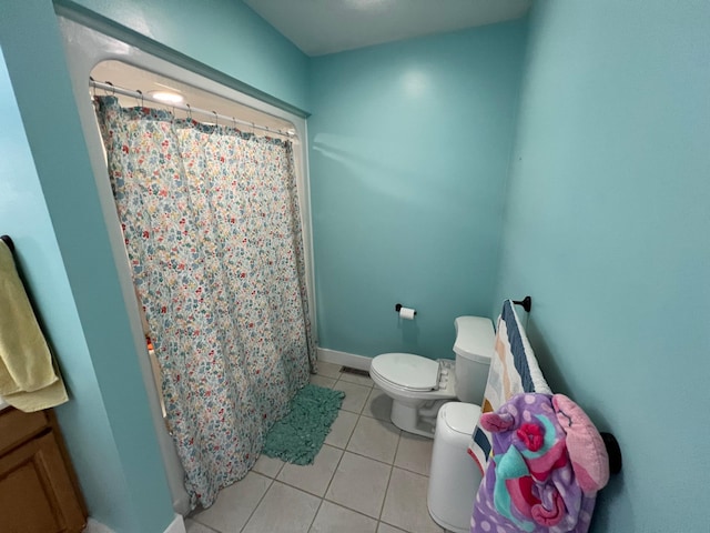 bathroom with toilet, a shower with curtain, tile patterned flooring, and baseboards