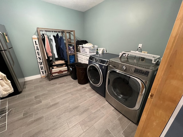 clothes washing area featuring laundry area, baseboards, a textured ceiling, wood finish floors, and separate washer and dryer