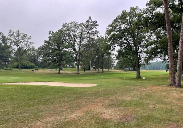 view of community featuring view of golf course and a lawn