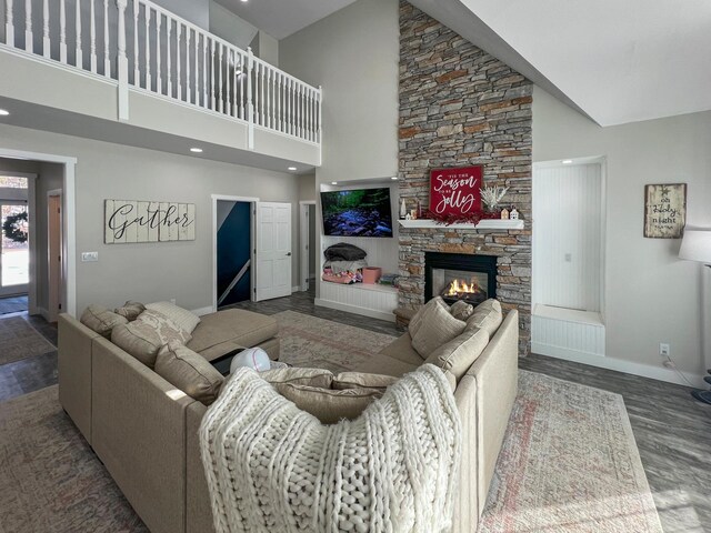 living area featuring a high ceiling, a fireplace, baseboards, and wood finished floors