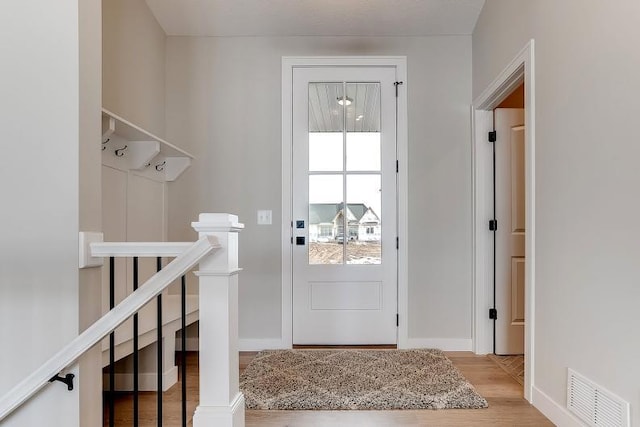 doorway to outside featuring wood finished floors, visible vents, and baseboards