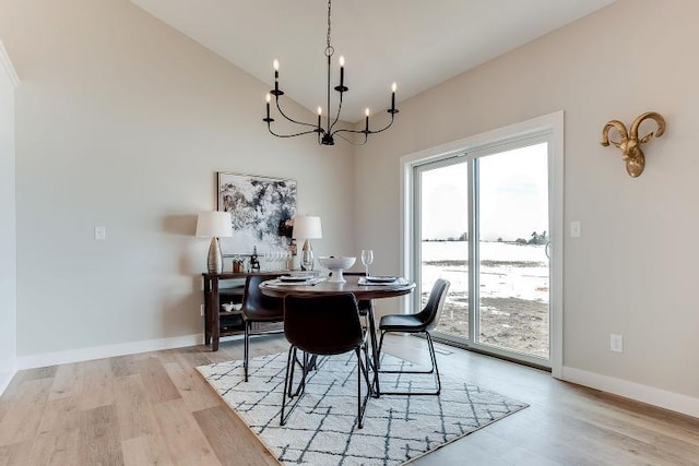 dining space featuring an inviting chandelier, light wood-style flooring, baseboards, and vaulted ceiling