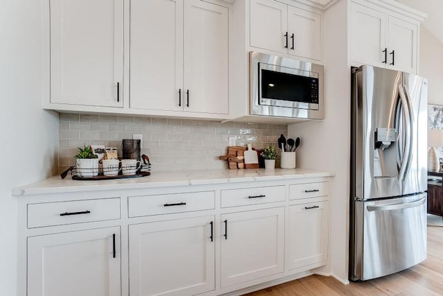 bar featuring appliances with stainless steel finishes, light wood-style floors, and tasteful backsplash