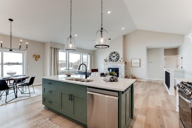 kitchen with a fireplace, light wood-style flooring, appliances with stainless steel finishes, a sink, and green cabinetry