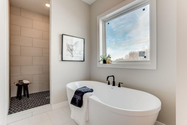 bathroom with a freestanding bath, tiled shower, tile patterned flooring, and baseboards