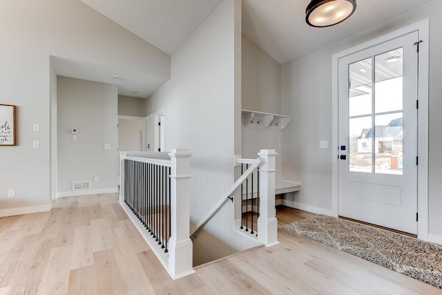 interior space with lofted ceiling, visible vents, light wood-style flooring, and baseboards