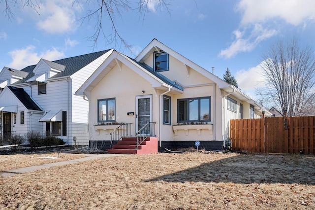 bungalow with fence and stucco siding