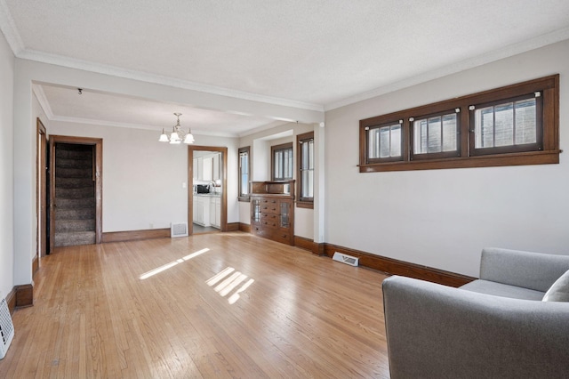 unfurnished living room featuring a chandelier, visible vents, baseboards, stairs, and light wood finished floors