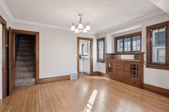 interior space with light wood-style floors, visible vents, and ornamental molding