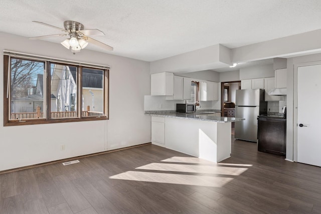 kitchen with stone counters, visible vents, appliances with stainless steel finishes, white cabinets, and a peninsula