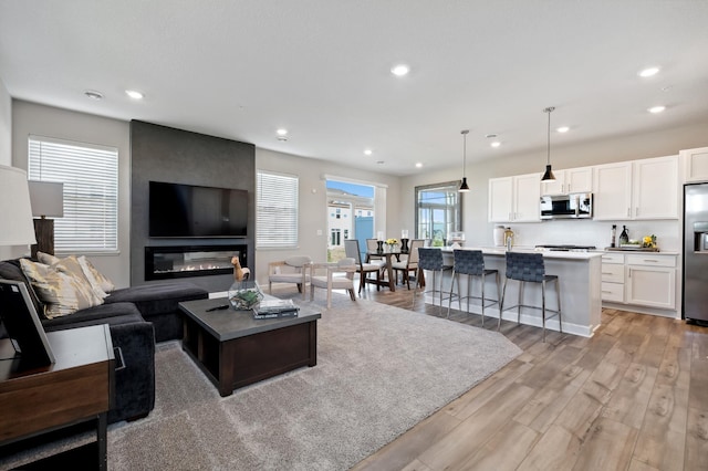 living room with light wood finished floors, a fireplace, and recessed lighting