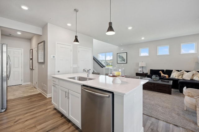 kitchen with stainless steel appliances, a sink, open floor plan, light countertops, and an island with sink